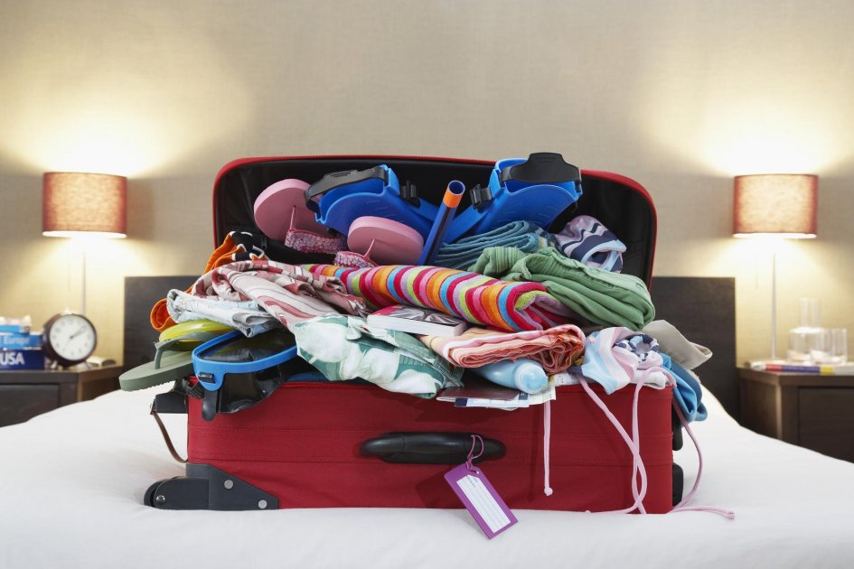 An open suitcase with clothes on the bed