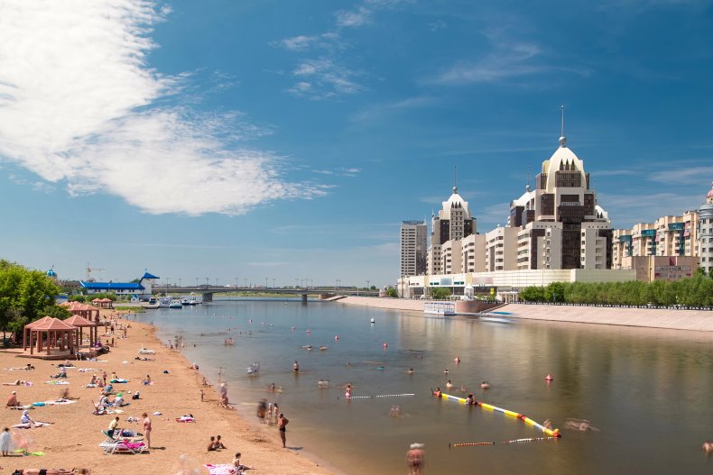 Люди купаються в річці вздовж штучного пляжного таймелапсу гіперлапс з мосту і горизонту Астани, Казахстан. Місто Нур-Султан 