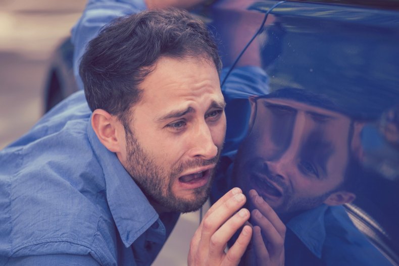 Un hombre examina los arañazos y las abolladuras del coche