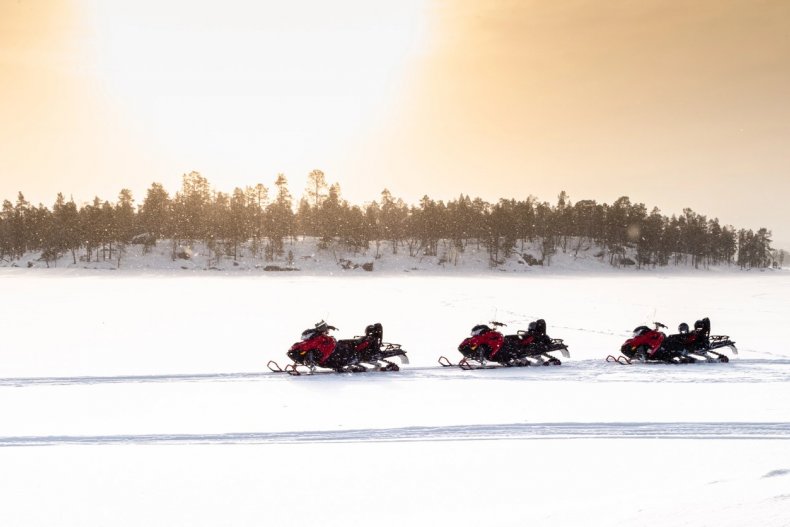 Un grupo de turistas en motos de nieve en una ruta invernal en Laponia