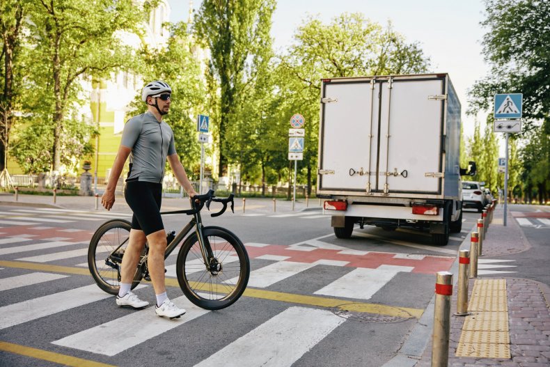 Un ciclista con casco cruza un cruce urbano por un paso de peatones