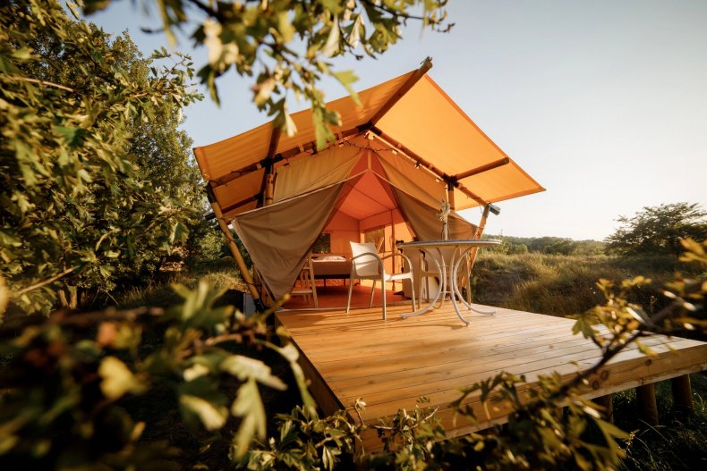 A cozy glamping tent with lighting, set against the backdrop of nature at sunset