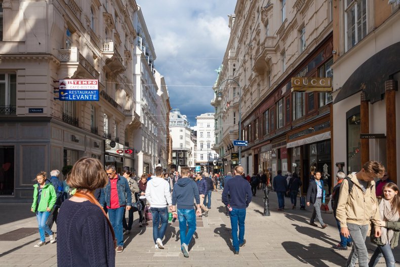 Tourists are strolling down a bustling shopping street lined with stores