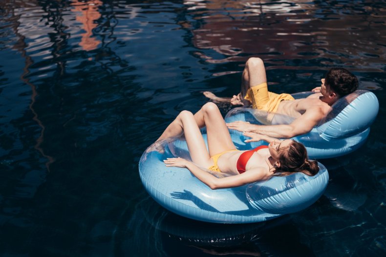 A couple is relaxing on inflatable rings in the pool